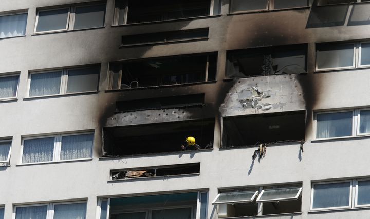 A fire fighter looks at the damage to the outside of a high-rise block in Wellington Way, Mile End, in east London, after a fire broke-out in a 12th floor flat on Friday