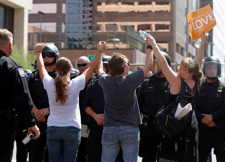 Demonstrators sand in front of riot police with their arms in the air during a protest against Arizona's controversial Senate Bill 1070 immigration law outside Sheriff Joe Arpaio's office in Phoenix July 29, 2010.