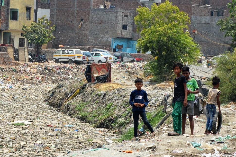 Nitesh Kumar (second from left) and friends play beside a canal covered in plastic waste near their homes in Geeta Colony, Ne