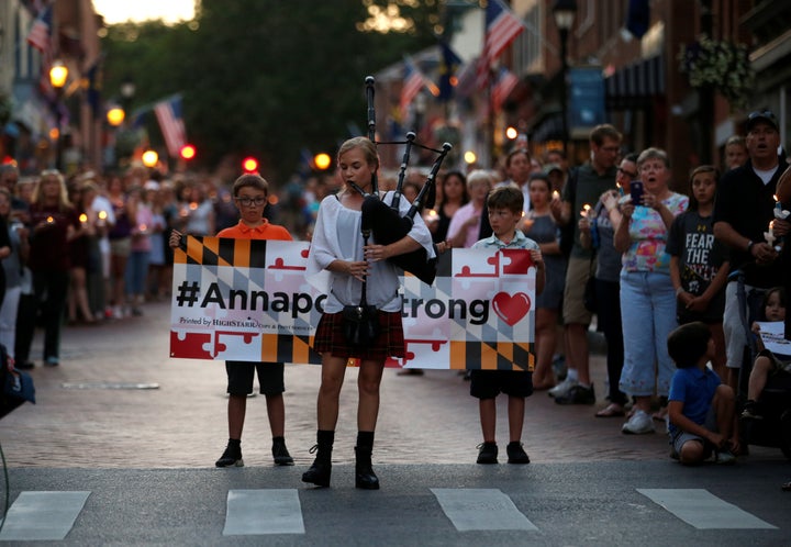 People line the street as a woman plays "Amazing Grace" on a bagpipe during a June 29 candlelight vigil in downtown Annapolis to honor the five people who were killed at the Capital Gazette offices.