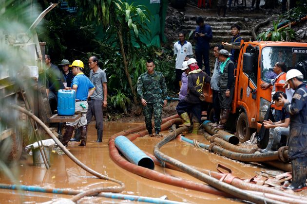 Soldiers and rescue workers work to clear water from the cave.