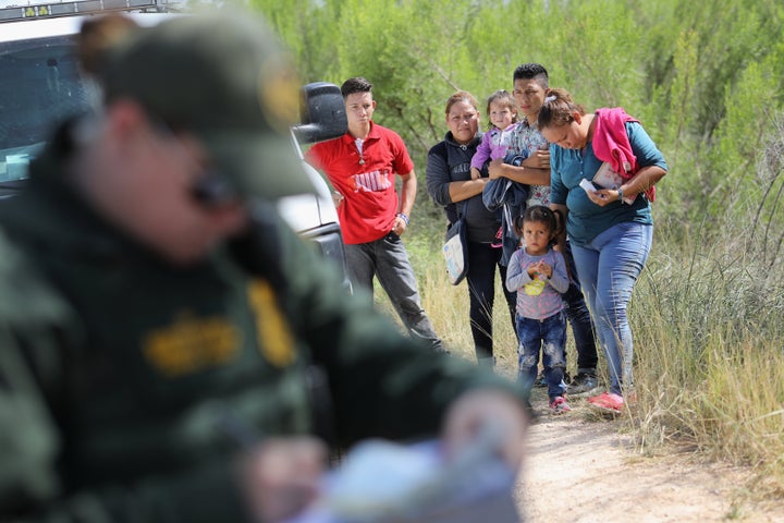 Central American asylum seekers wait as U.S. Border Patrol agents take groups of them into custody on June 12 near McAllen, Texas.