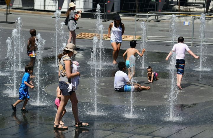 Women and children play in the water fountains at the Place des Arts in Montreal on Tuesday.