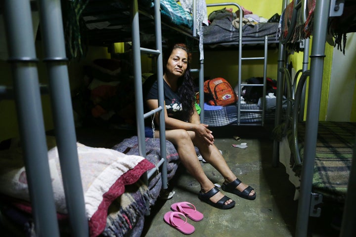 A migrant mother of three, from western Mexico, poses while sitting on her bed in the room where women and children sleep in