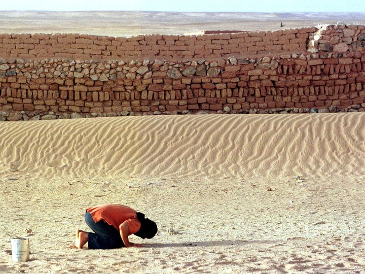 A Moroccan prisoner of war prays beside the wall of a Saharawi prison in the Algerian desert