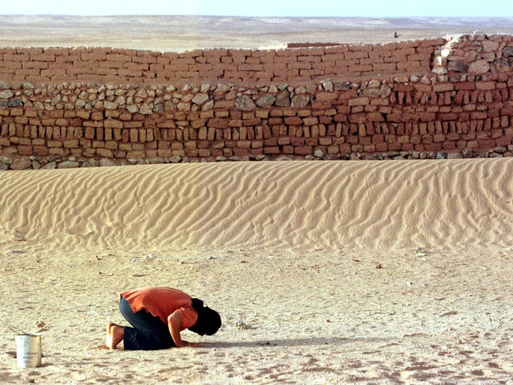 A Moroccan prisoner of war prays beside the wall of a Saharawi prison in the Algerian desert