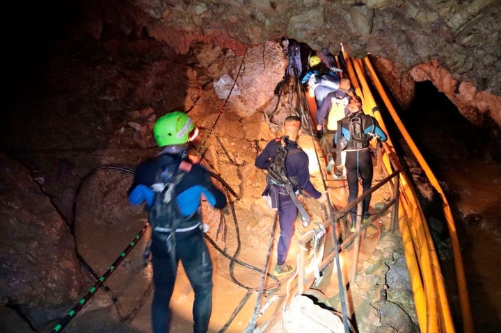 Thai rescue team members walk inside the cave