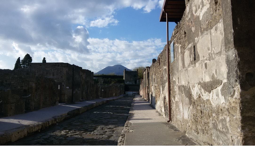 Κεντρική οδό της Πομπηίας. Στο βάθος το ηφαίστειο, ο Βεζούβιος και δεξιά η οικία των Βέττι (CasadeiVetti)