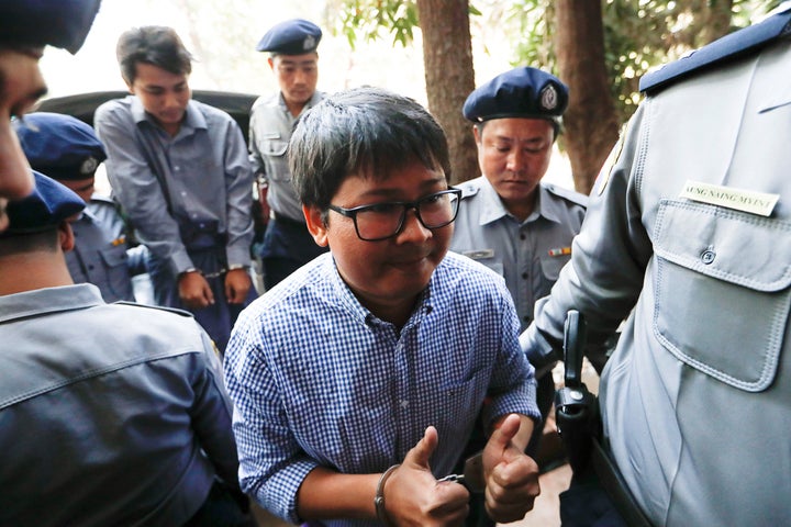 Journalist Wa Lone gives two thumbs up while being escorted by police into a court hearing back in February. Fellow journalist Kyaw Soe Oo follows behind him, also in handcuffs.