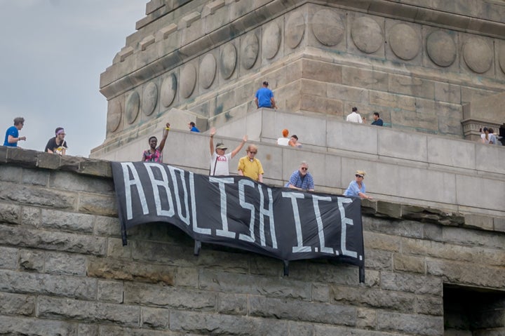 Protesters hang an “Abolish ICE” banner at the base of the Statue of Liberty on July 4. Congress established Immi