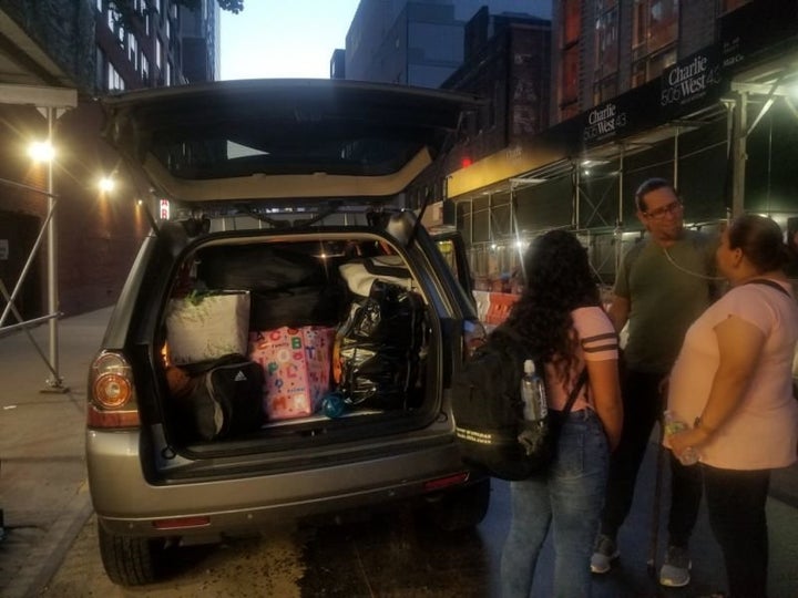 A childhood friend and fellow evacuee helps Jenyffer Ortiz pack her belongings into a car. 