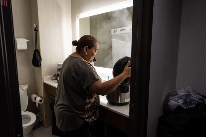 Jenyffer Ortiz cooks chicken in a rice cooker in the hotel bathroom, where there is counter space. She cooks for herself to better deal with diabetes and other ailments. 