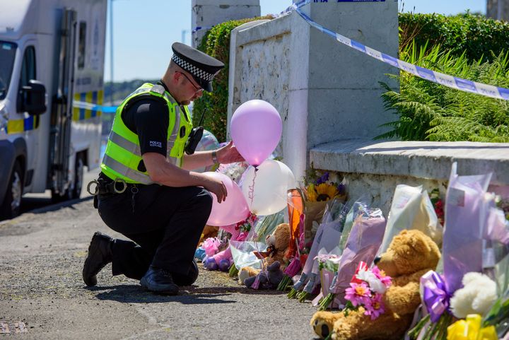 A police officer leaves balloons at a house close to where Alesha's body was found 
