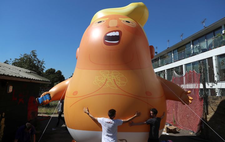 People inflate a helium filled Donald Trump blimp which is due to fly over the capital during the US President's visit