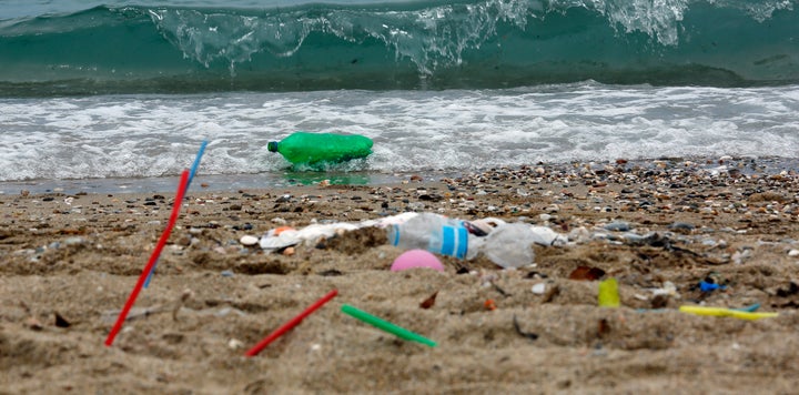 Plastic garbage, including straws, lies on the Aegean Sea beach near Athens, Greece.