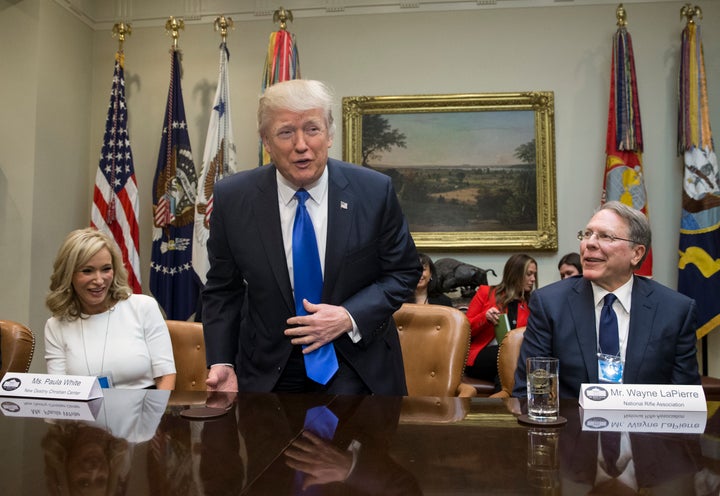 President Donald Trump takes a seat between White and National Rifle Association leader Wayne LaPierre at a White House meeting on Feb. 1, 2017.