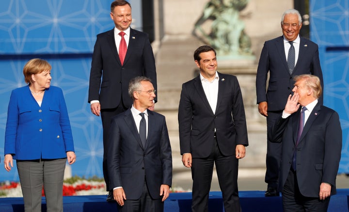 German Chancellor Angela Merkel (L) looks on as U.S. President Donald Trump speaks to other leaders as they pose for a family photo at the Park of the Cinquantenaire during the NATO Summit in Brussels, Belgium, on July 11, 2018. 