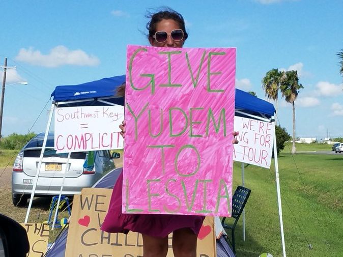 The author holds a sign reading "Give Yudem To Lesvia." The photo was taken by Norma Herrera from Grassroots Leadership through her car window as she was driving Lesvia away from Casa El Presidente.
