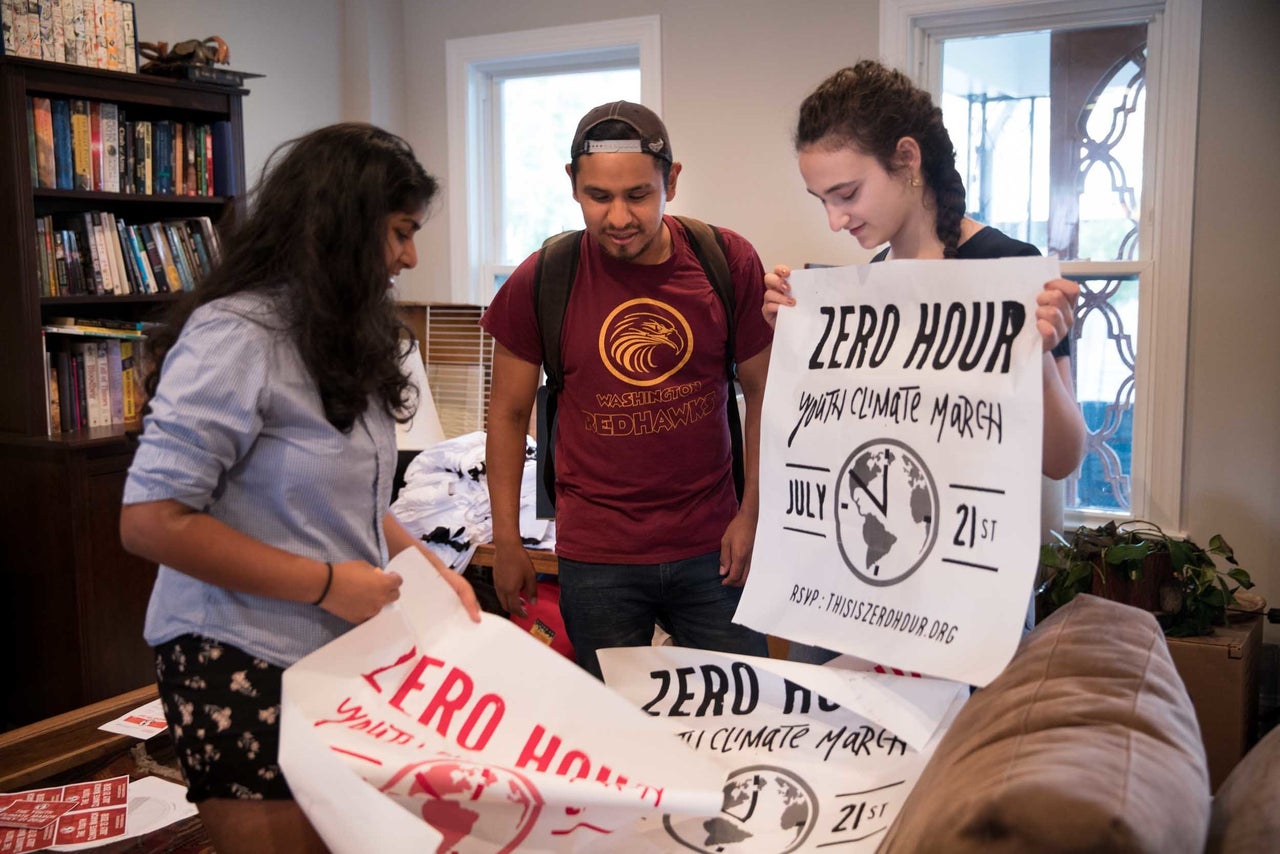 Jair Carrasco, center, shows new posters to Jamie Margolin and Nadia Nazar.