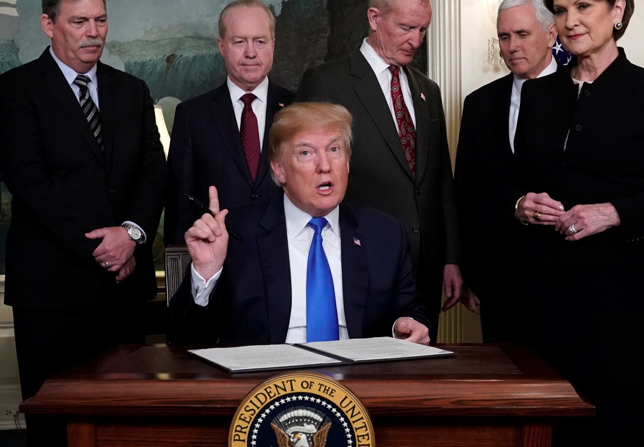 U.S. President Donald Trump, surrounded by business leaders and administration officials, prepares to sign a memorandum on intellectual property tariffs on high-tech goods from China, at the White House in Washington, U.S. March 22, 2018.