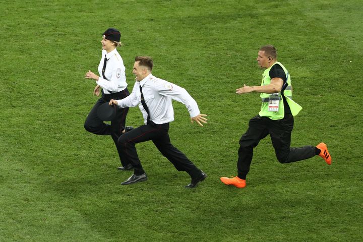 A man and woman are seen being chased by guards after invading the field at the World Cup final Sunday.