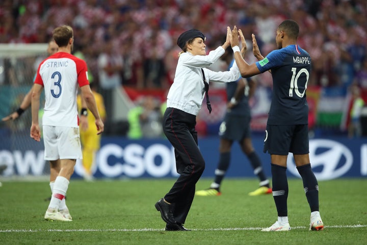 A woman high-five's Kylian Mbappe of France after running onto the field.