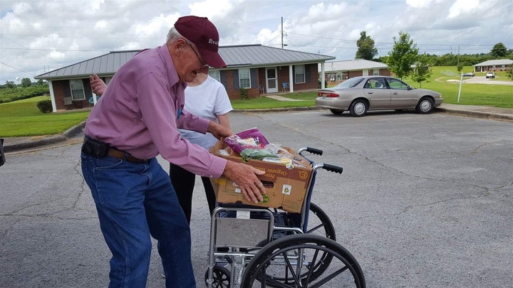 John Seals, 83, of Hackleburg, Alabama, uses a wheelchair to carry a box of food from a West Alabama Food Bank truck.
