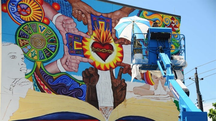 Artist Michelle Santos at work on a mural near the Sacred Heart of Jesus Church in southeast Baltimore.