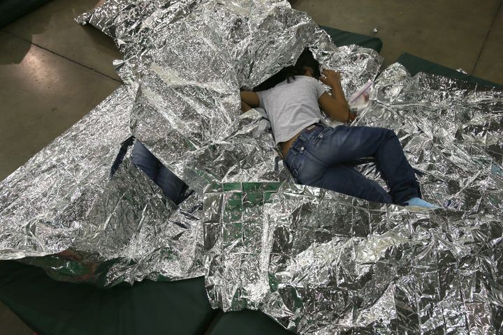 A girl from Central America rests on thermal blankets at a detention facility run by the U.S. Border Patrol on Sept. 8, 2014, in McAllen, Texas. 