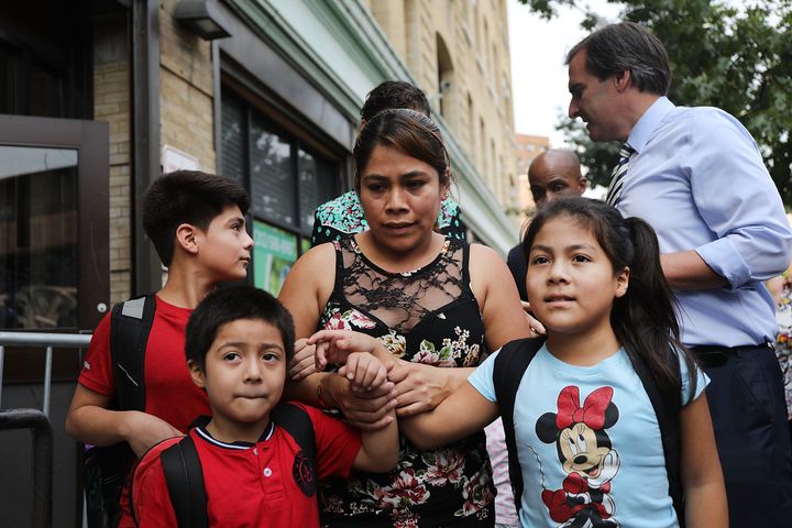 Yeni Maricela Gonzalez Garcia holds fast to 11-year-old Lester, left, 6-year-old Deyuin and, 9-year-old Jamelin and as she and her lawyer speak with the news media after she was reunited with her children at the East Harlem Cayuga Centers on July 13 in New York City.