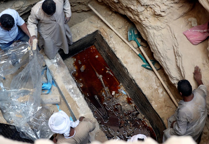 Workers open a coffin containing skeletal remains lying in sewage water in Alexandria, Egypt, on Thursday.