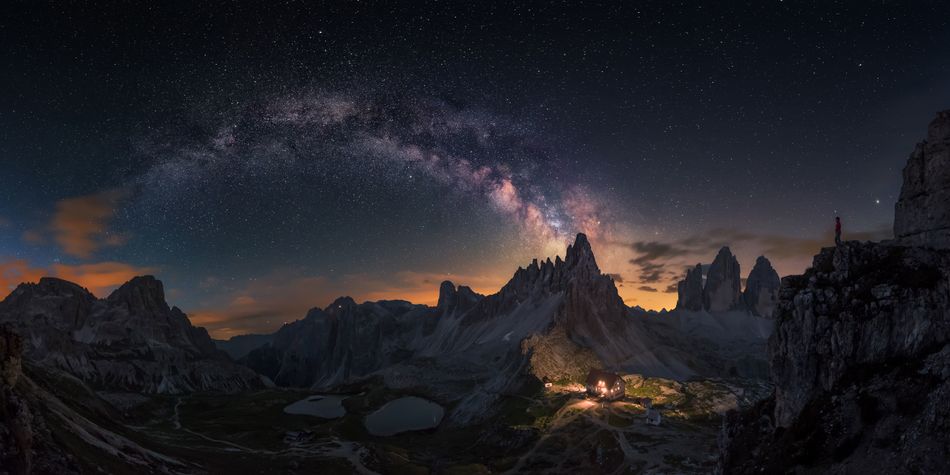 This panoramic image composed out of eight photos depicts the Milky Way emerging over the rocky Dolomites in Tre Crime on the left and on the right the lights from a house illuminating the beautiful terrain The photographer noted that the image represents sharing unforgettable moment with the ones you love Tre Cime Italy 25 June 2017