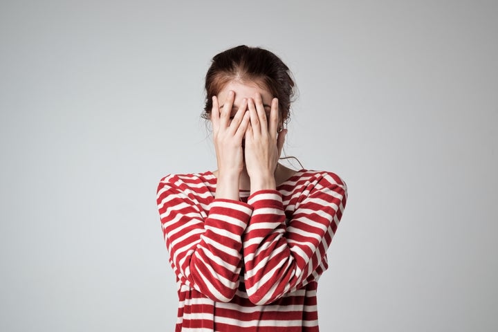 Image of a woman with both of her hands over her face.