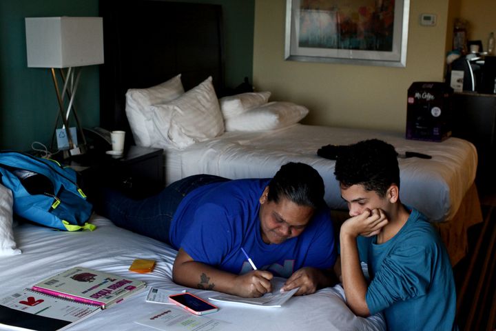 Liz Vazquez helps her son Raymond Fernandez Vazquez with his homework in an Orlando, Florida hotel room, where they've been living since being displaced by Hurricane Maria, on December 6, 2017.