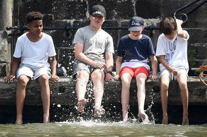 Children splash in water as they dangle their feet into Bristol's Floating Harbour during the Harbour Festival in the city centre during hot sunny weather on Saturday.