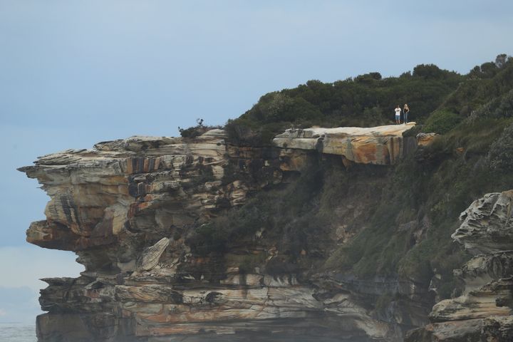 Spectators watch a surfing event from headland at Cape Solander