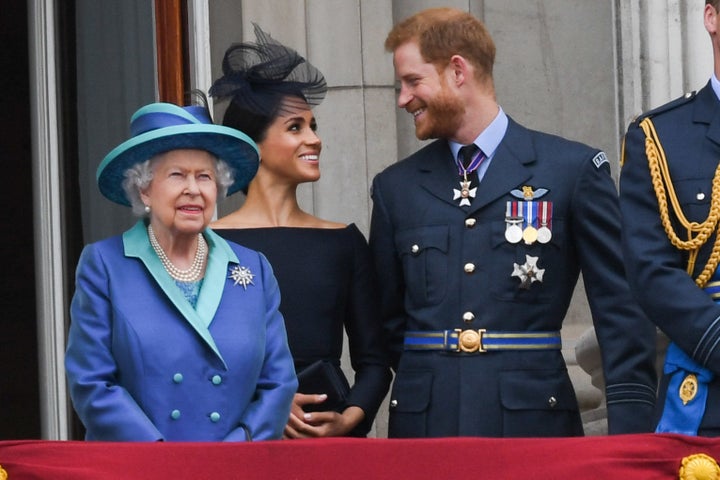   Queen Elizabeth II, Meghan, the Duchess of Sussex and Prince Harry, Duke of Sussex, stand on the balcony of Buckingham Palace at 