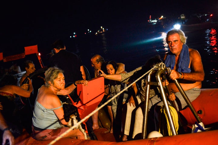 Rescuers and volunteers help local people evacuate the village of Mati.