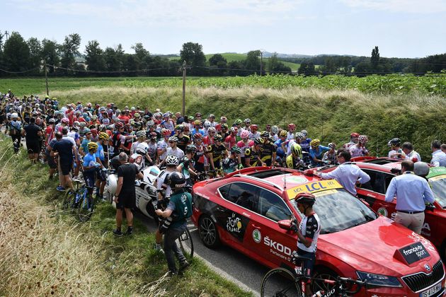 The pack of riders waits for the stage to resume, after tear gas was used during a farmers' protest who attempted to block the 16th stage's route.