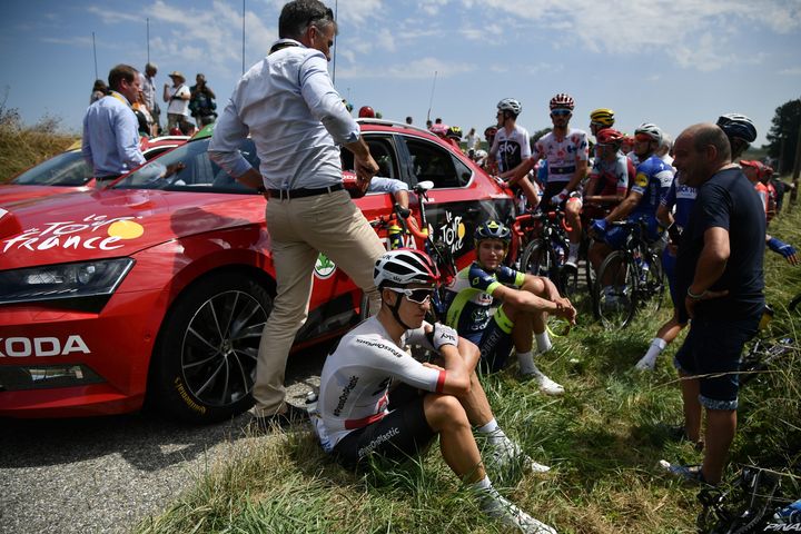 Riders sit after General Director of the Tour de France, France's Christian Prudhomme (Rear L) halted the race.