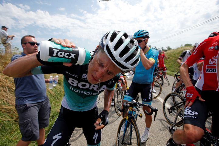 BORA-Hansgrohe team rider Pawel Poljanski of Poland cleans his eyes after police used pepper spray to disperse the crowd.