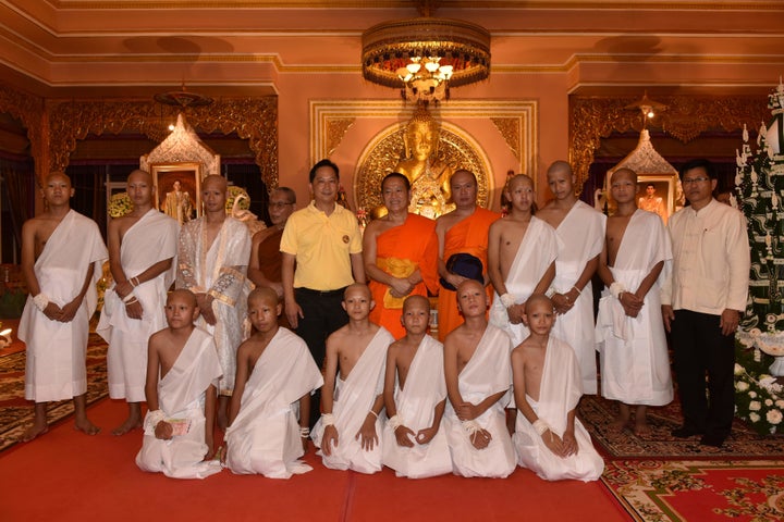 Eleven members of the Wild Boars soccer team and their coach wear white robes at a Buddhist te