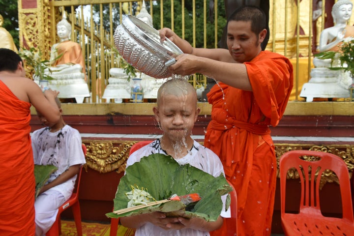 A Buddhist monk bathes the shaved head of a rescued Thai boy on Tuesday.