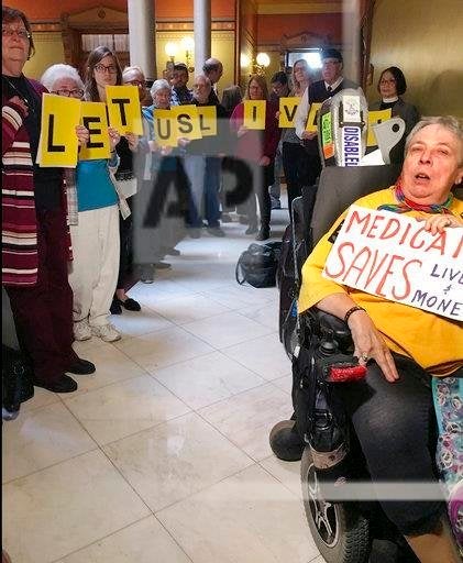 Activists, urging Connecticut state legislative leaders not to cut Medicaid spending, wait outside the room where a new two-year, bipartisan budget agreement was being negotiated, Wednesday, Oct. 18, 2017, at the Capitol in Hartford, Conn. 