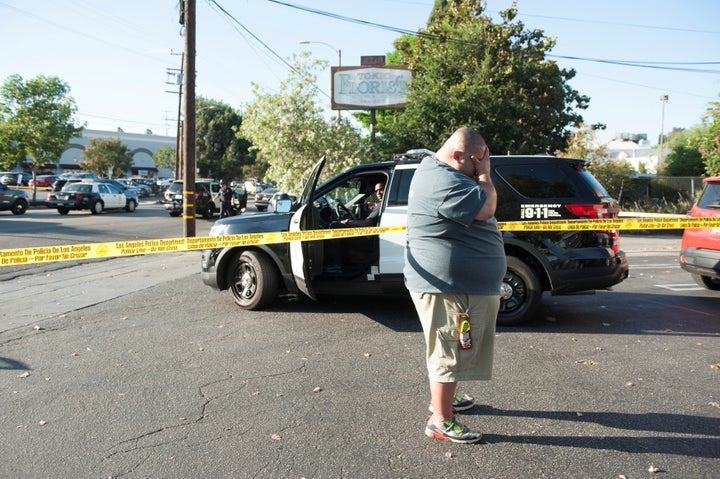 A Trader Joe's employee waits in a parking lot near the grocery store where a hostage situation unfolded in Los Angeles on Saturday.