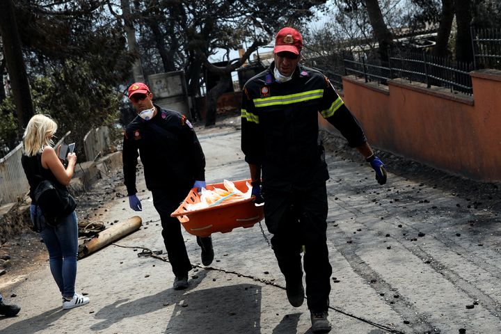 Firefighters carry a stretcher filled with body bags, following a wildfire at the village of Mati, near Athens, Greece.