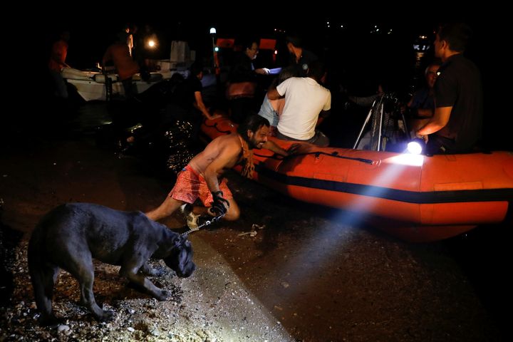 A man holding a dog pushes an inflatable boat as locals are evacuated during a wildfire at the village of Mati, near Athens.