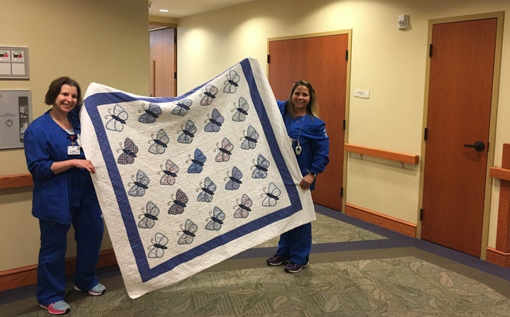 Tammy Wright, left, and Carrie Merk, hospice nursing assistants at the Medina Inpatient Hospice Care Center, hold up a quilt embroidered with butterflies that is used to cover deceased patients after they are bathed and before the funeral home arrives. The quilt was made and donated by volunteers and is meant to help soothe families who may be seeing loved ones for the last time.