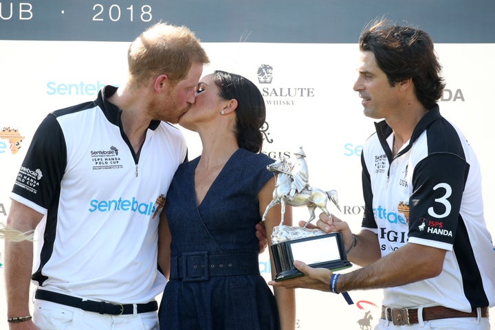 Nacho Figuares of presents the Sentebale Polo 2018 trophy as Meghan, Duchess of Sussex and Prince Harry, Duke of Sussex, kiss. 