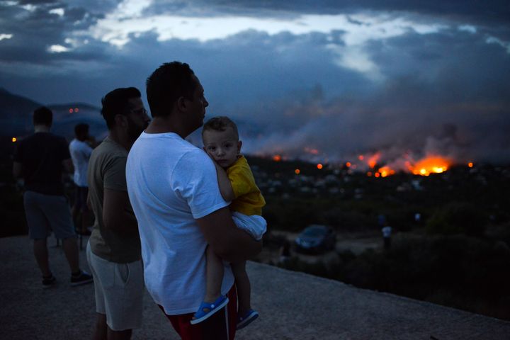 A man holds his son as a wildfire burns in the town of Rafina, near Athens, on July 23, 2018.